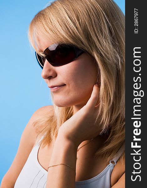 The girl in glasses on a blue background in studio