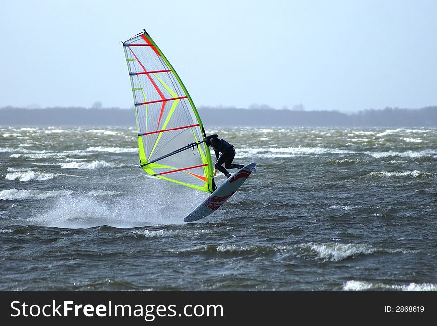 Windsurfer performing an Airjibe. Stormy weather. Windsurfer performing an Airjibe. Stormy weather.