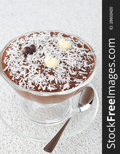 Chocolate mousse in a glass sundae dish with chocolate hearts decorated with coconut on a white background
