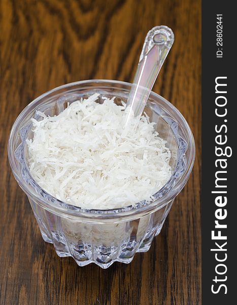 Unsweetened coconut flakes in a transparent jar on a wooden table
