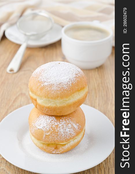 Sweet donuts sprinkled with powdered sugar on a plate and a cup of coffee. Sweet donuts sprinkled with powdered sugar on a plate and a cup of coffee