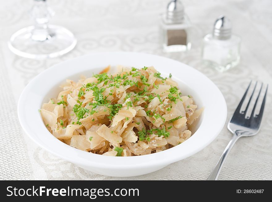 Fried Cabbage with greens and eggs in the white plate closeup