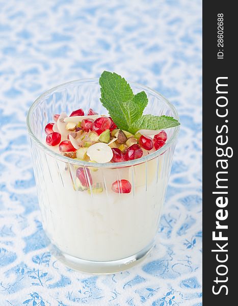 Semolina dessert with pomegranate seeds and pistachios garnished with mint in a glass beaker