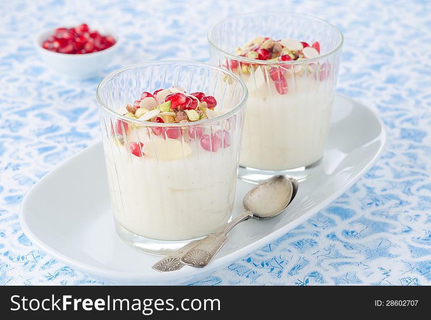 Semolina dessert with pomegranate seeds and pistachios in glass beakers on a plate horizontal. Semolina dessert with pomegranate seeds and pistachios in glass beakers on a plate horizontal