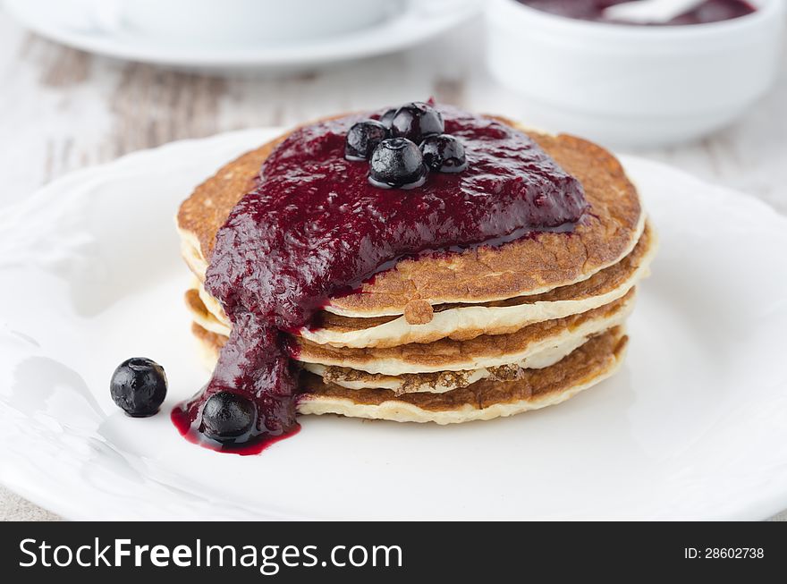 Stack of pancakes with black currant jam on the plate closeup, horizontal