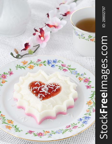 Two-layer dessert of cream and jam and coconut on white plate