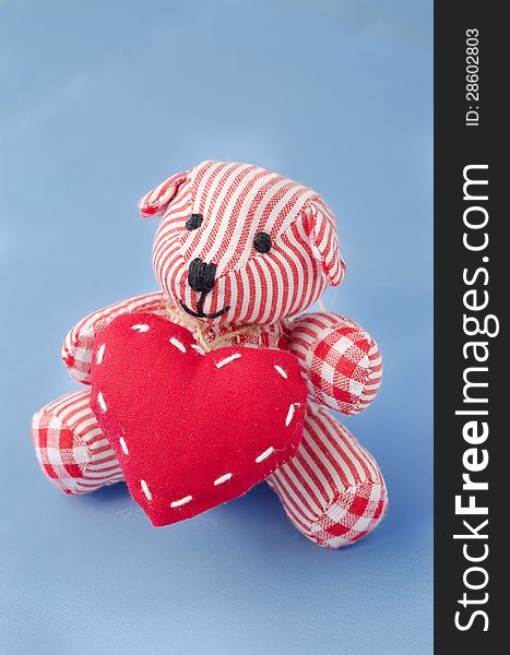 Teddy bear with a heart in his hands on a blue background
