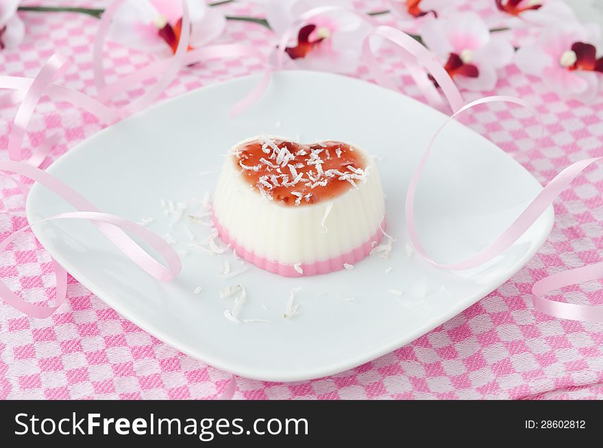 Two-layer cream dessert in the form of heart with coconut on a plate horizontal