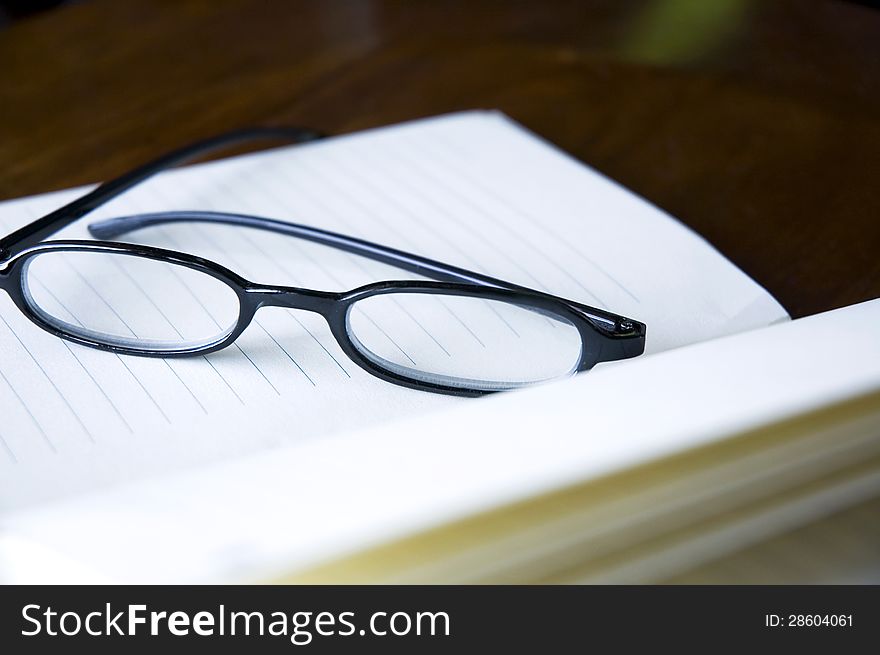 Close up eyeglasses put on open notebook