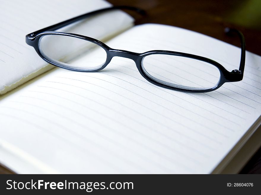 Eyeglasses put on blank notebook. Eyeglasses put on blank notebook