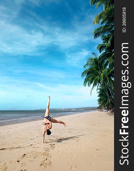 A young woman doing cartwheels on the beach