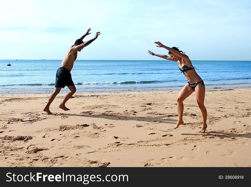 A young men and women doing cartwheels on the beach