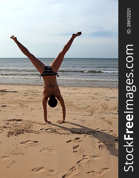 A young woman doing cartwheels on the beach