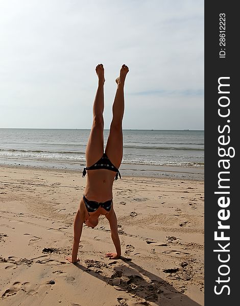 Young woman makes a handstand at the sea. Young woman makes a handstand at the sea