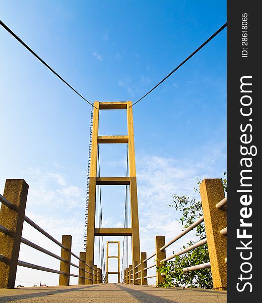 Cable bridge pole with concrete way and blue sky background