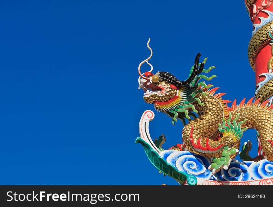 Colorful Chinese Dragon around the red pole on blue sky background