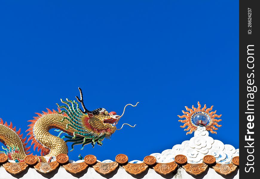 Chinese Dragon and sun sculpture on the temple roof with blue sky background. Chinese Dragon and sun sculpture on the temple roof with blue sky background