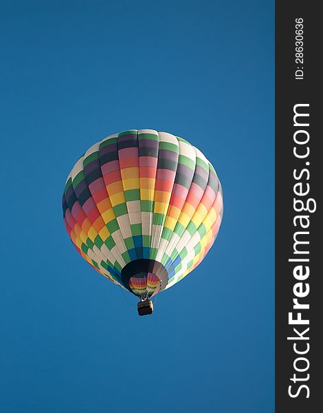 Hot air balloon over farm land with blue sky