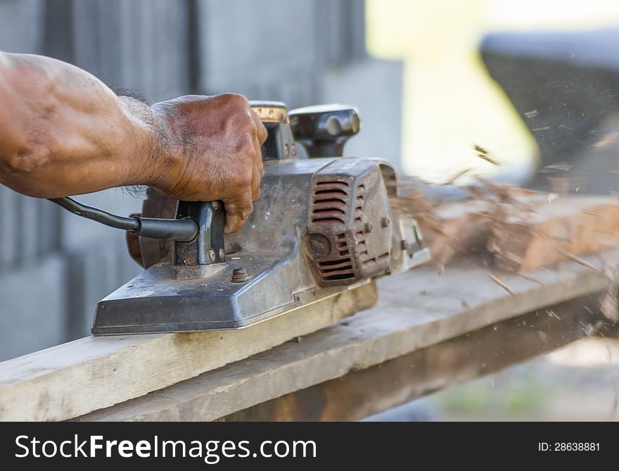 Carpenter working with electric planer