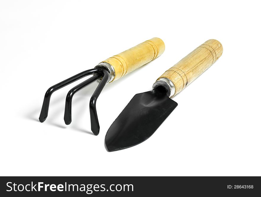 Steel rake and shovel with a wooden handle on white background