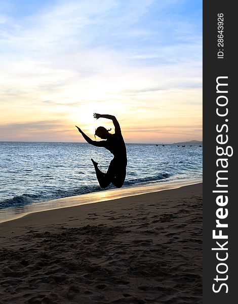 Silhouette jumping woman on a beach. Sunset