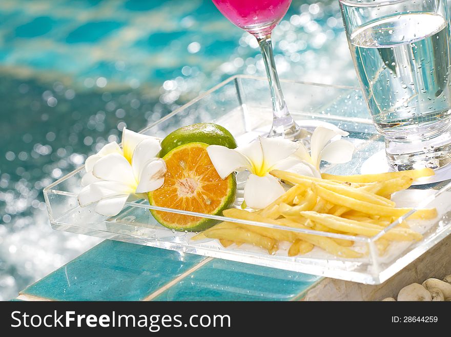 French-fries and orange in snack tray by the pool