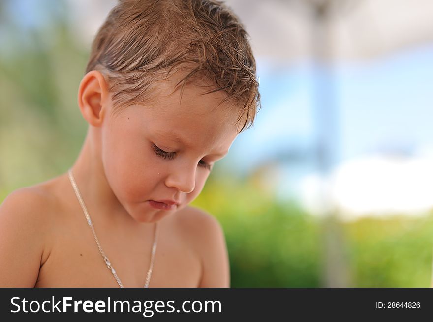 Close up the person of the sad boy with wet hair on the nature. Close up the person of the sad boy with wet hair on the nature