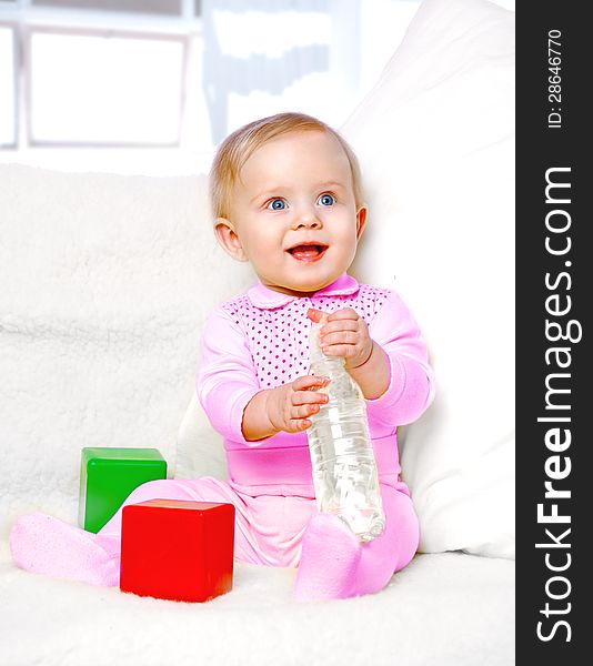 Portrait of a cheerful little girl drinking water from a bottle