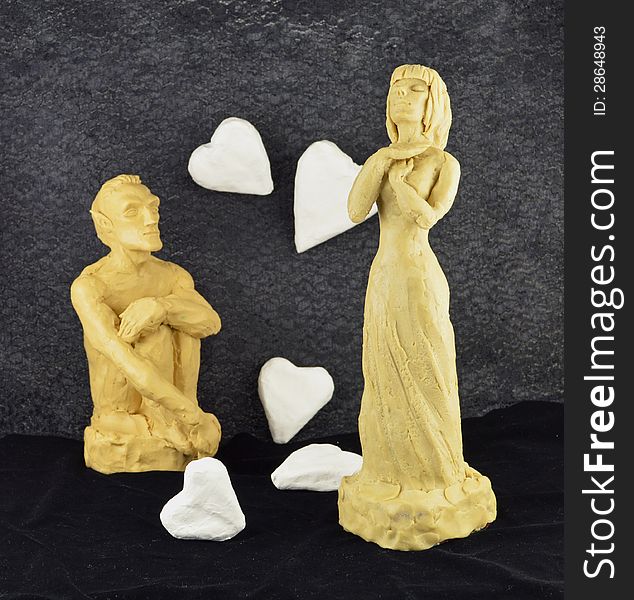 Man and woman made of clay with white paper hearts. Man and woman made of clay with white paper hearts