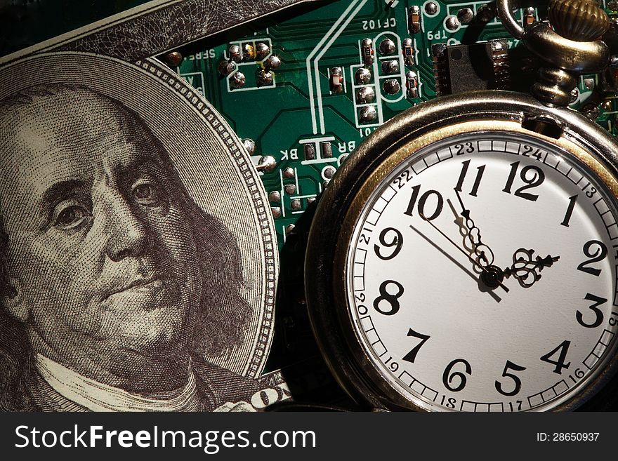 Business concept. Closeup of one hundred dollar note near watch on green computer mainboard. Business concept. Closeup of one hundred dollar note near watch on green computer mainboard