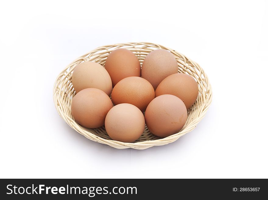 Brown eggs in bamboo basket on white background.