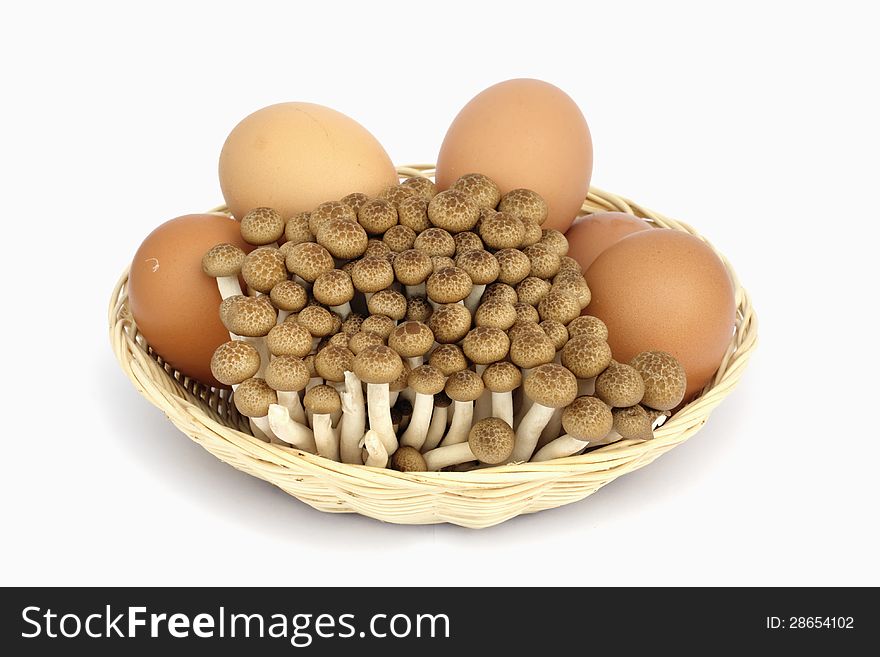 Brown eggs and mushroom in bamboo basket on white background. Brown eggs and mushroom in bamboo basket on white background