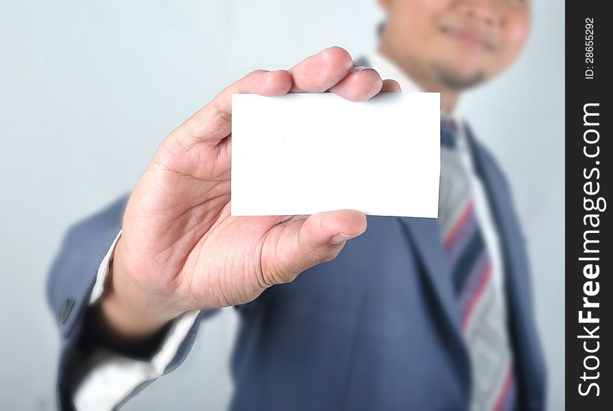 Business man show blank card in front of grey background