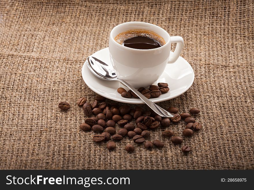 Cup of coffee, grains on burlap background