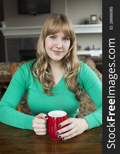 Portrait of a young woman staring straight ahead into the camera holding a cup of coffee. Portrait of a young woman staring straight ahead into the camera holding a cup of coffee.