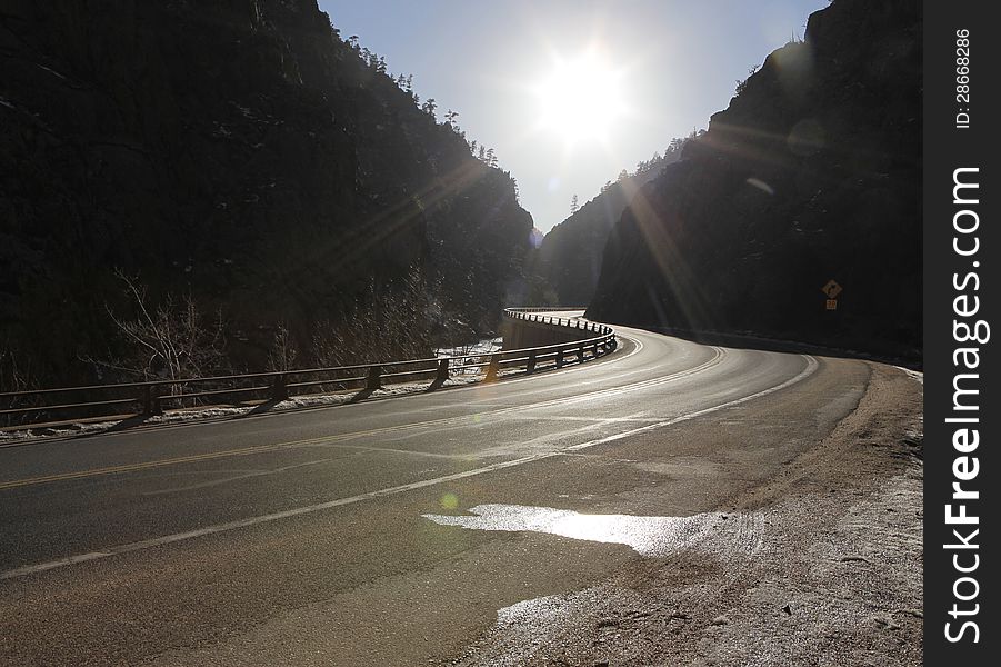 Sunlight shines on an old mountain road leading into the mountains.