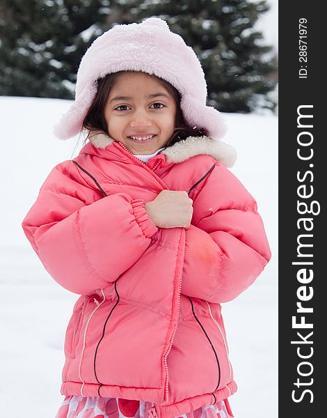 A beautiful East Indian girl child clutches to her jacket in the snow. A beautiful East Indian girl child clutches to her jacket in the snow.