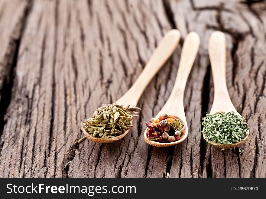 Variety of spices in the spoons on an old wooden table. Variety of spices in the spoons on an old wooden table.