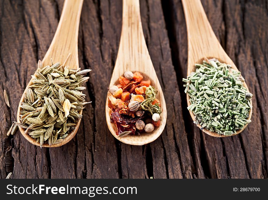 Variety of spices in the spoons on an old wooden table. Variety of spices in the spoons on an old wooden table.