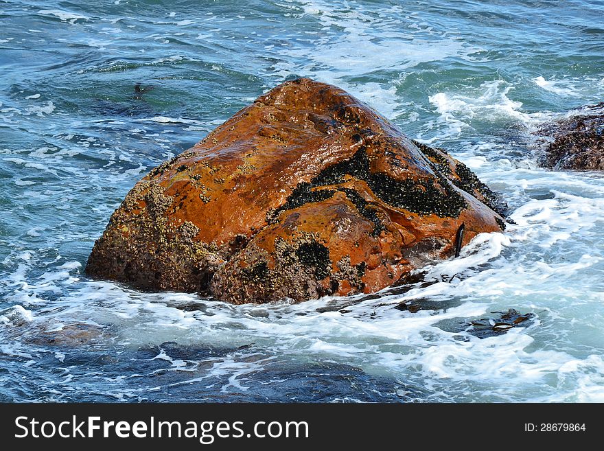 Close up of red rock in the atlantic ocean with waves. Close up of red rock in the atlantic ocean with waves