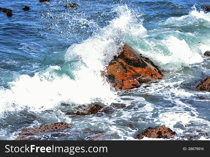 Close up of red rock in the atlantic ocean with waves. Close up of red rock in the atlantic ocean with waves