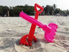 Red And Pink Sand Rake Toys In Beach Sand And People Background Taken In Jakarta Indonesia Stock Photography