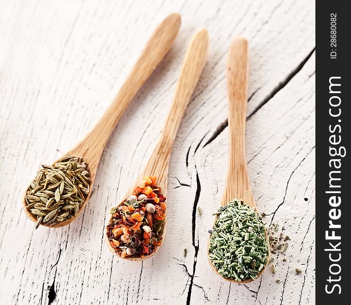 Variety of spices in the spoons on an white old wooden table. Variety of spices in the spoons on an white old wooden table.