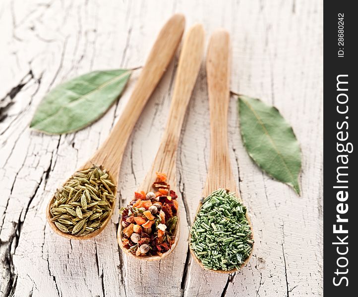 Variety of spices in the spoons on an white old wooden table. Variety of spices in the spoons on an white old wooden table.