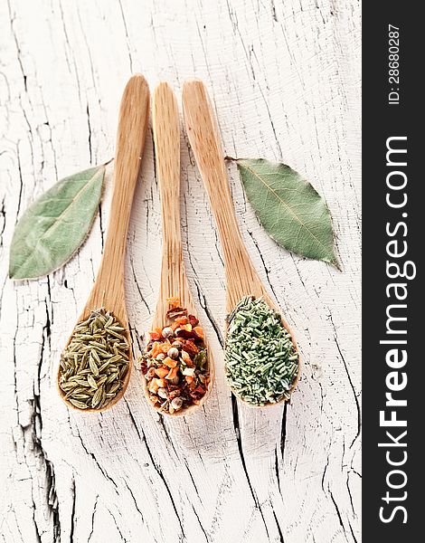 Variety of spices in the spoons on an white old wooden table. Variety of spices in the spoons on an white old wooden table.