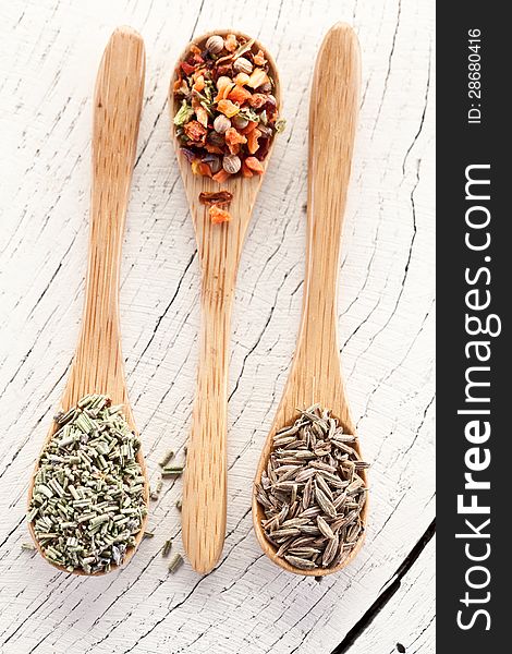 Variety of spices in the spoons on an white old wooden table. Variety of spices in the spoons on an white old wooden table.