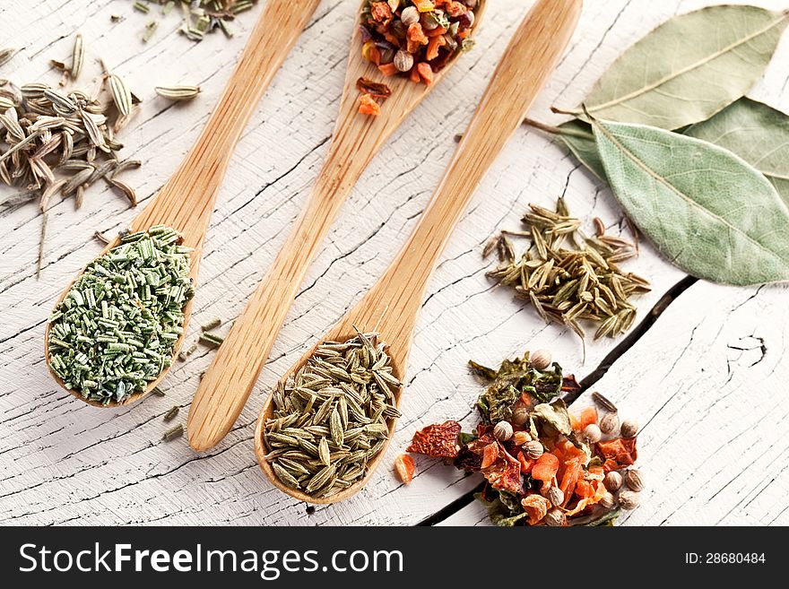 Variety of spices in the spoons on an white old wooden table. Variety of spices in the spoons on an white old wooden table.