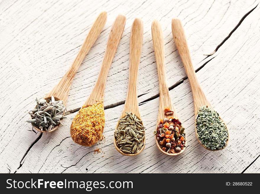 Variety of spices in the spoons on an white old wooden table. Variety of spices in the spoons on an white old wooden table.