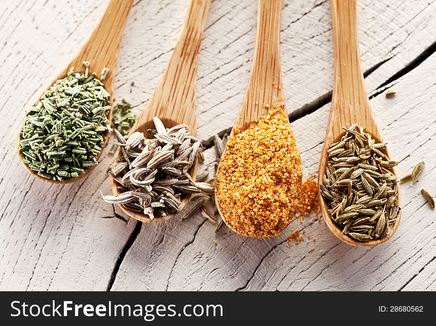 Variety of spices in the spoons on an white old wooden table. Variety of spices in the spoons on an white old wooden table.