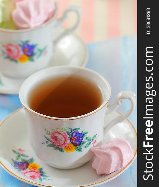 Black tea in elegant cup with colorful meringue cookies. Black tea in elegant cup with colorful meringue cookies